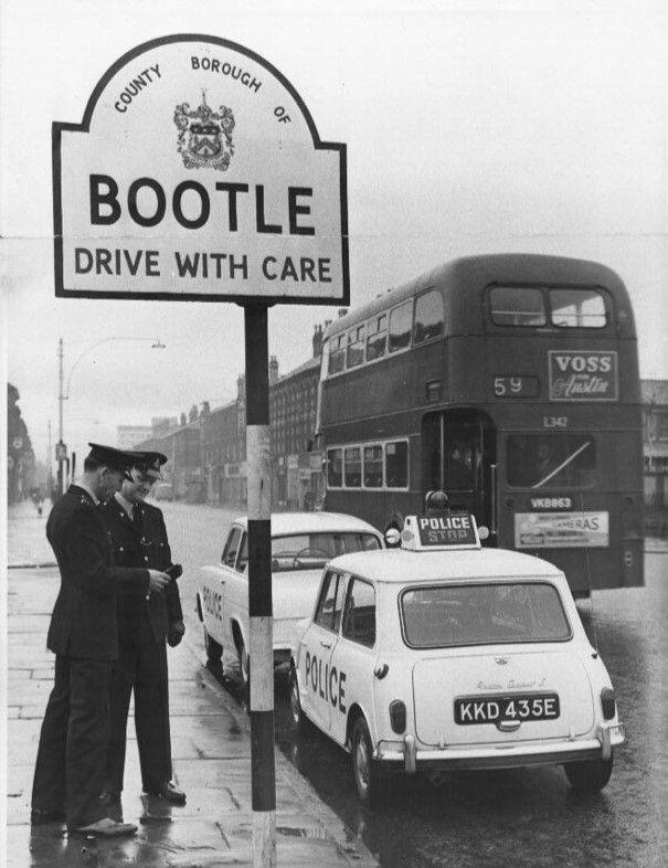 Austin Mini Cooper S MkI KKD 435E behind a Ford Anglia police car at Bootle, with rear POLICE/STOP roof board and aerial mounted above the driver’s-side tail lamp.